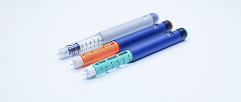Drei farbige Insulin-Pens liegen nebeneinander