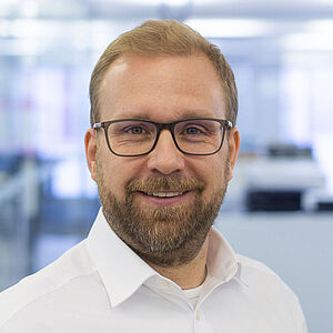 Smiling man in a white shirt. In a well-lit office.