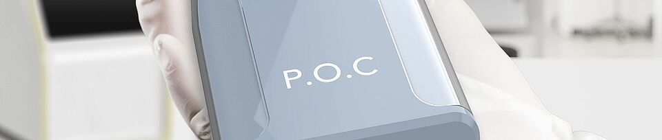 POC Device in einer Hand mit Handschuh, im Hintergrund ein Labor mit großer Fensterfront