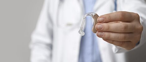 Doctor holding a hearing aid in his hand